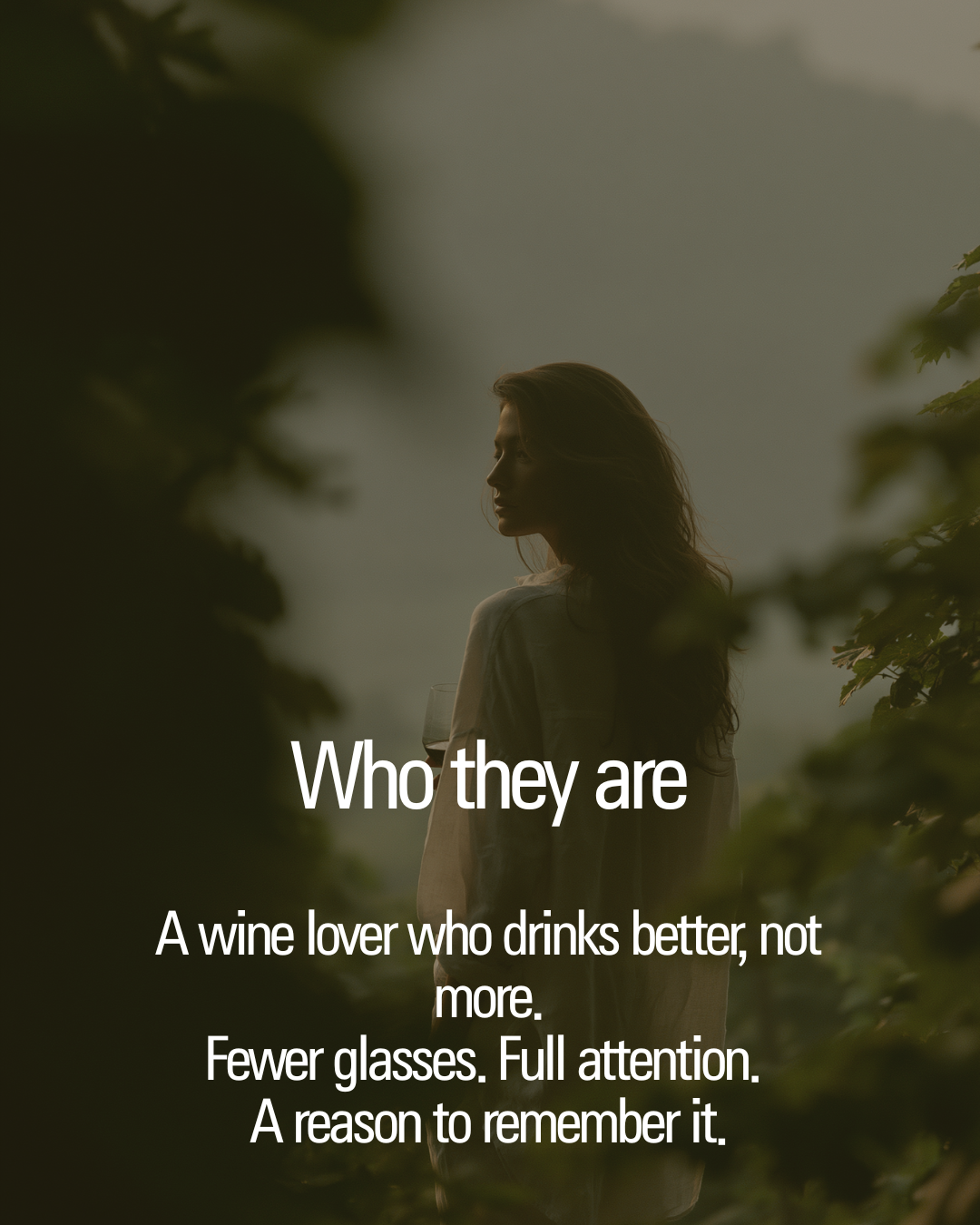 Woman holding a wine glass among vineyard rows.